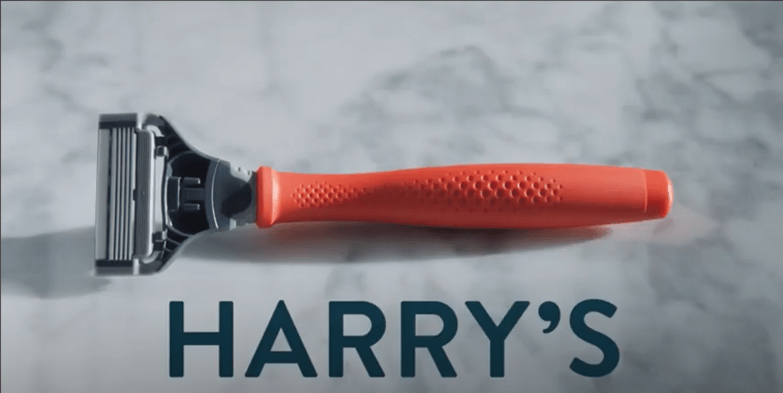 A red Harry's razor on a marble surface featuring the Harry's logo